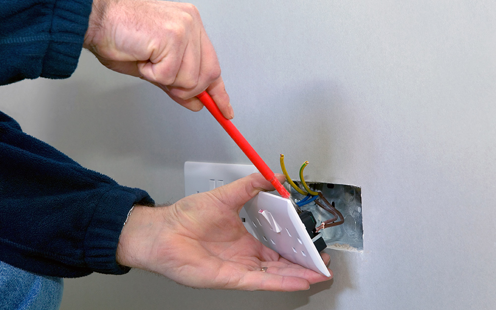 Person removes an outlet cover. 