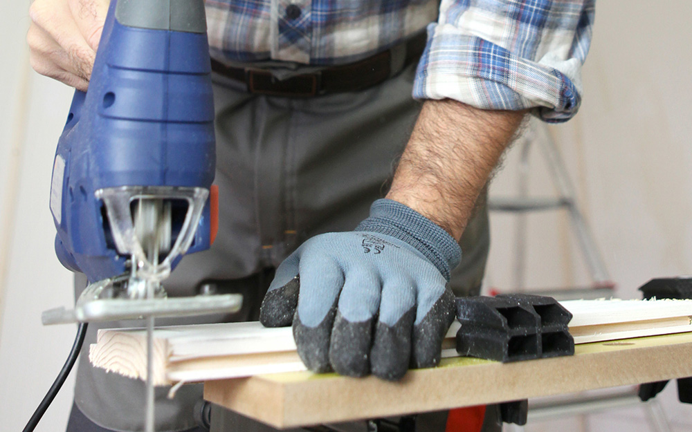 Person uses a saw to cut wainscoting panels. 