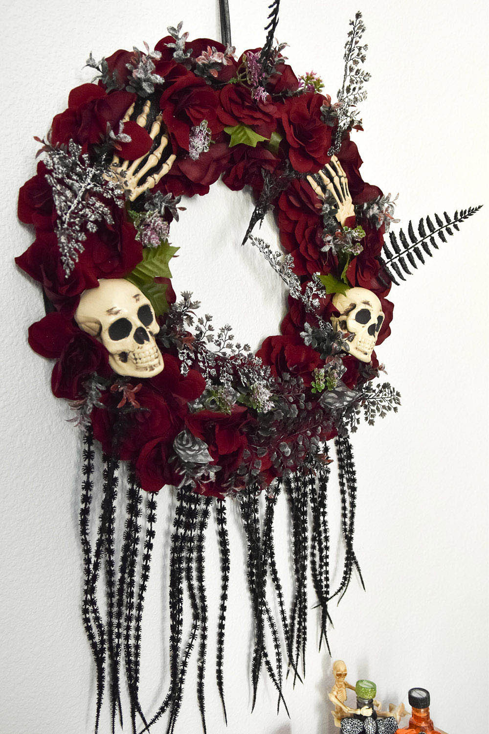 An indoor Halloween wreath of red flowers and skulls.