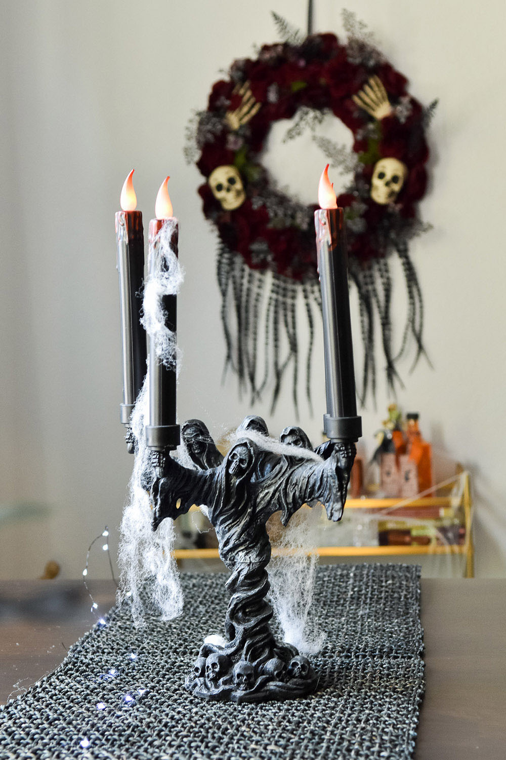 A dining room decorated with a spooky candelabra and indoor wreath with skulls.