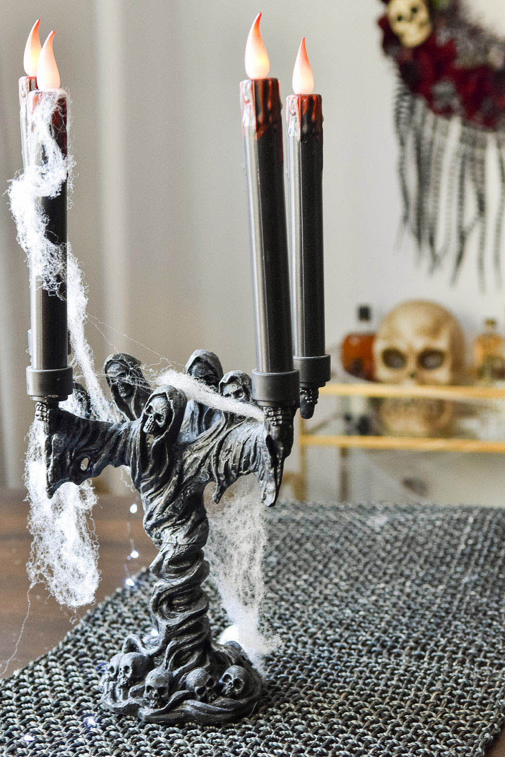 A spooky Halloween candelabra sitting on a dining room table runner.