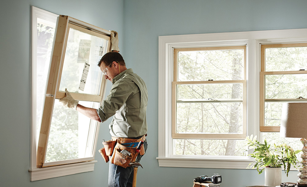 A man installs an egress window in a room.