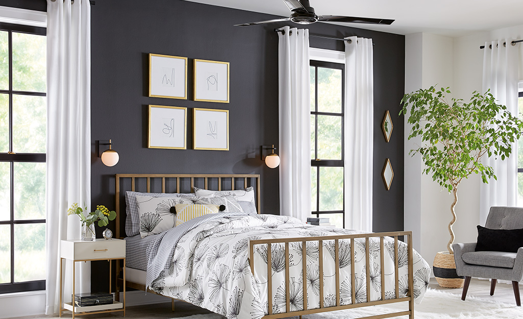 A bedroom with long white drapes on the windows.