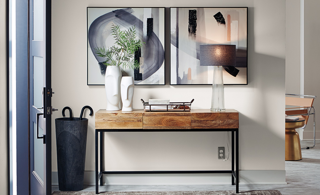 Small console table next to door with white vases.