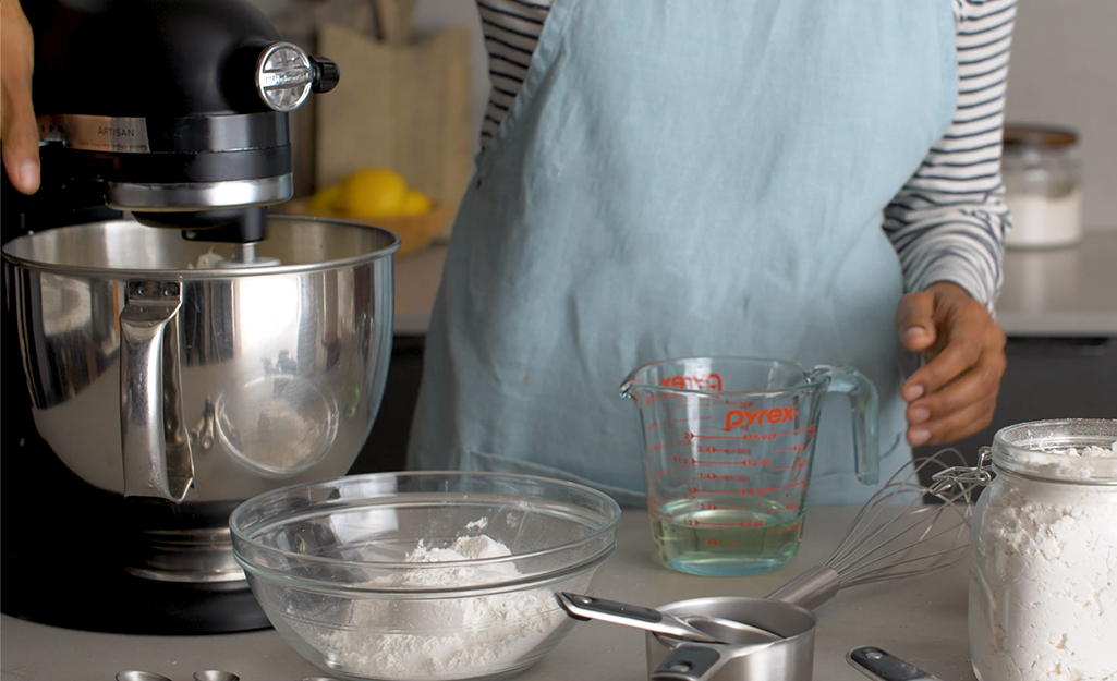 A stand mixer sitting on a countertop with a glass mixing bowl and measuring cup