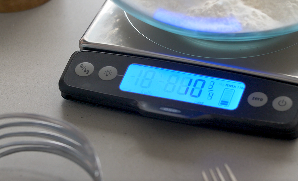 Flour in a glass mixing bowl being weighed on a digital scale