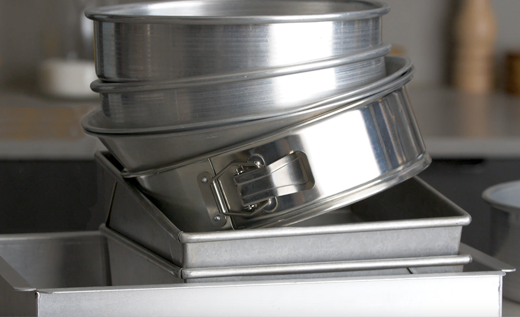 A stack of circular silver cake pans placed on top of square baking pans