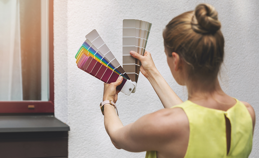 A woman looks at the paint swatches she is holding.