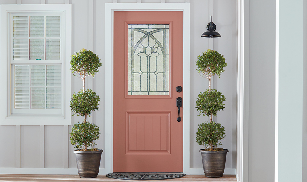 A coral door stands out against a home’s light gray exterior paint.