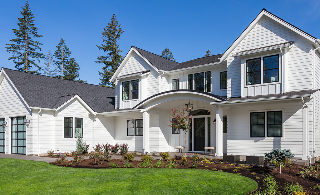 A white two-story house stands out against a bright blue sky.