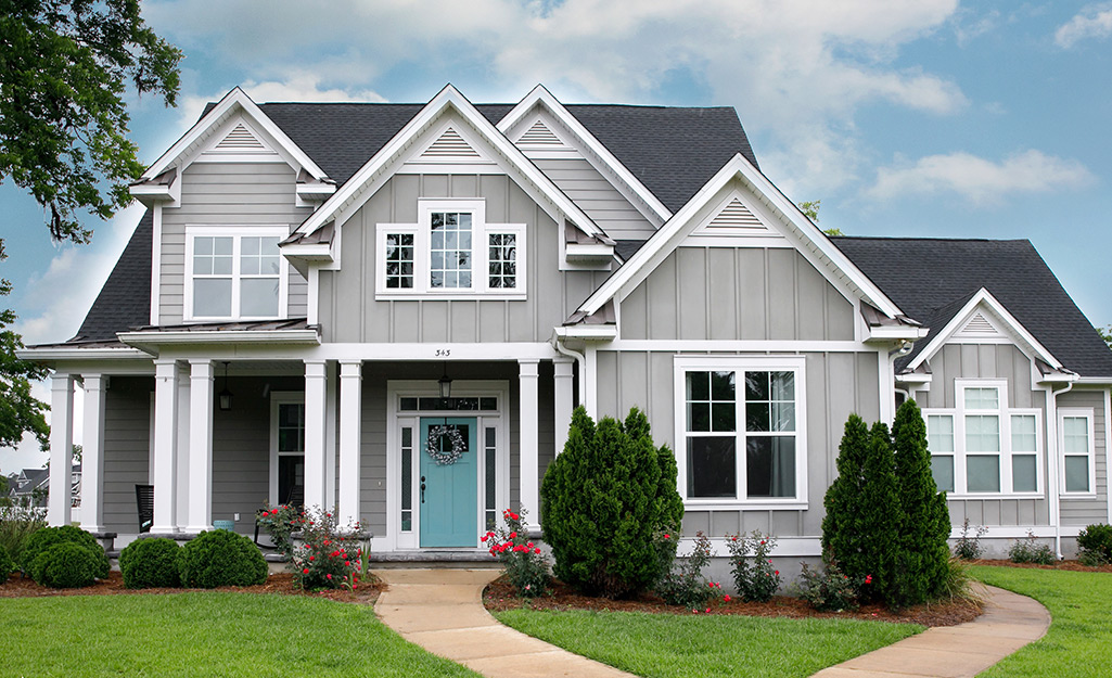 White trim and a turquoise front door accent a two-story home painted pale gray.