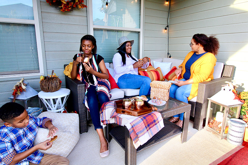 A group of people sitting on a Fall decorated patio.