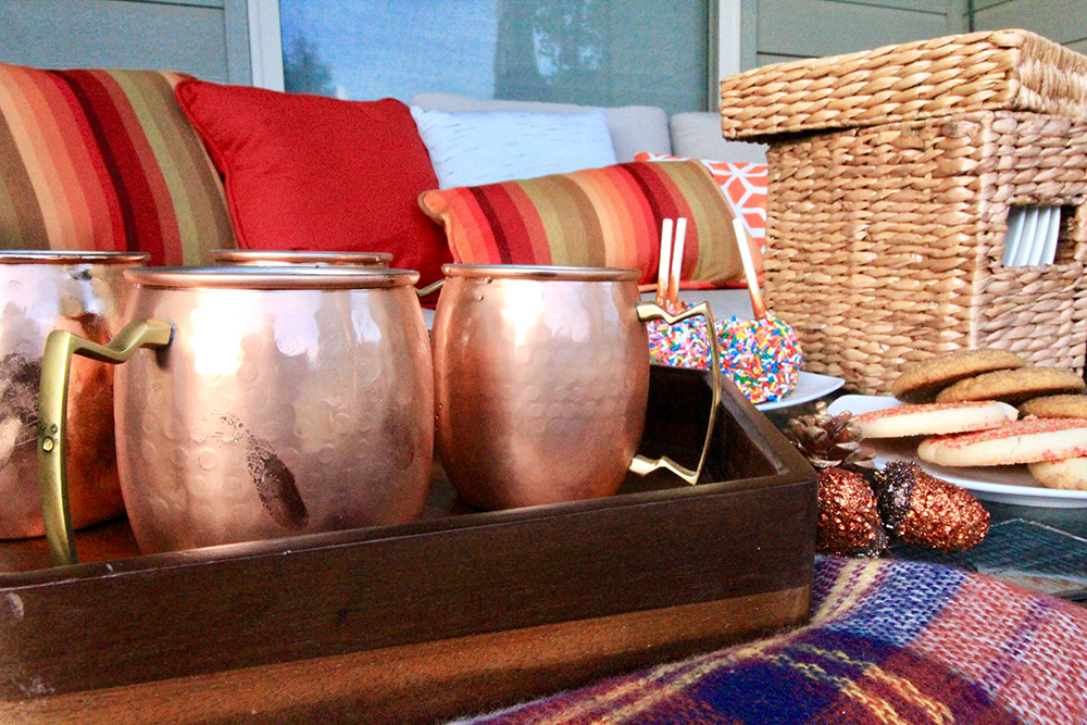 A group of copper mugs sitting on a wooden tray.