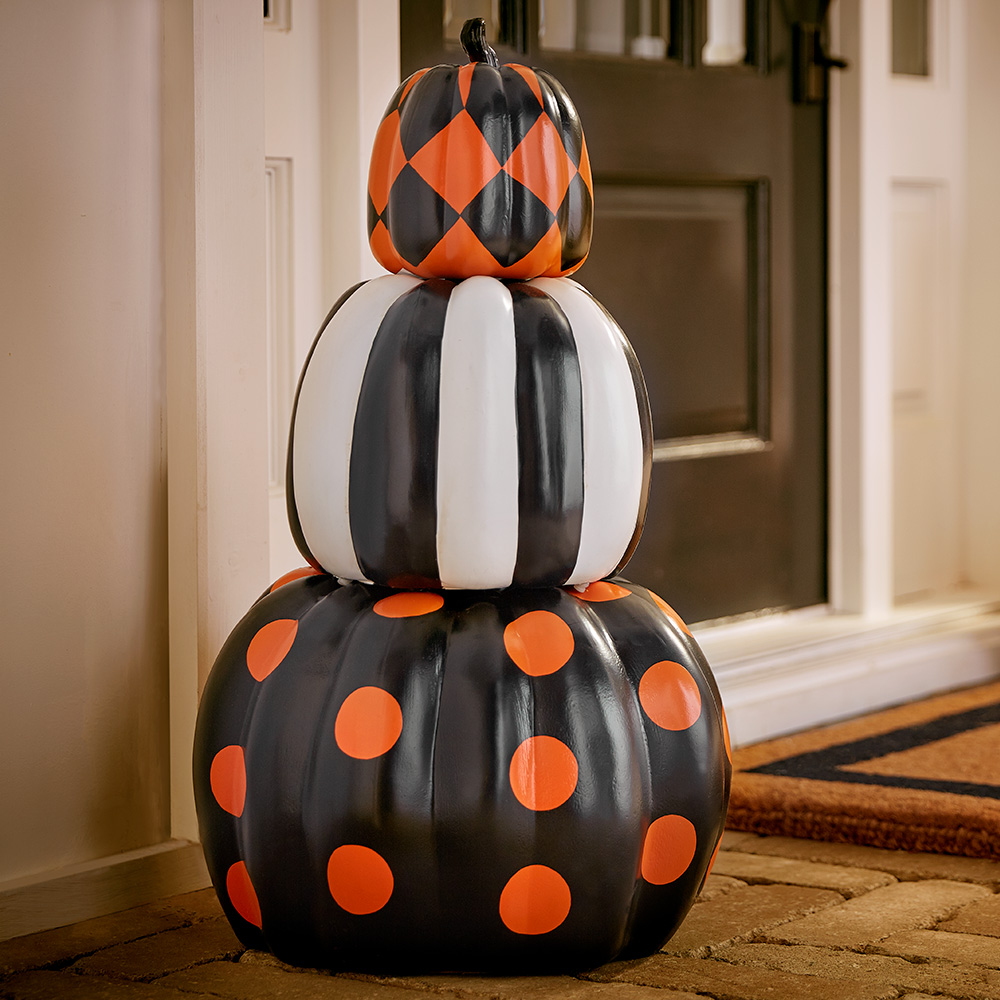 Decorated pumpkins stacked on a porch.