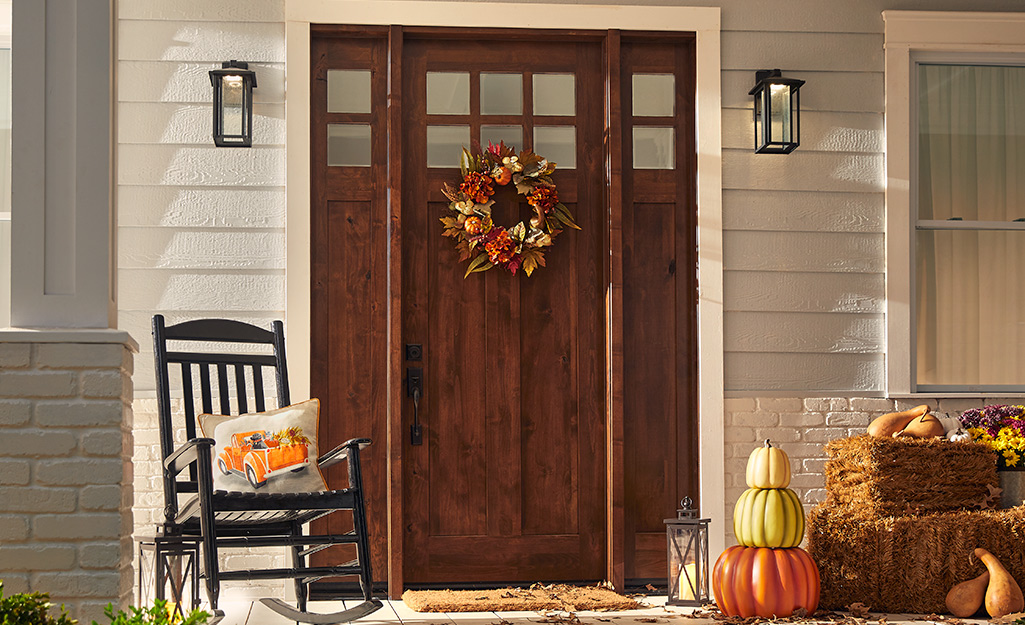 Fall porch decor that includes a fall wreath.