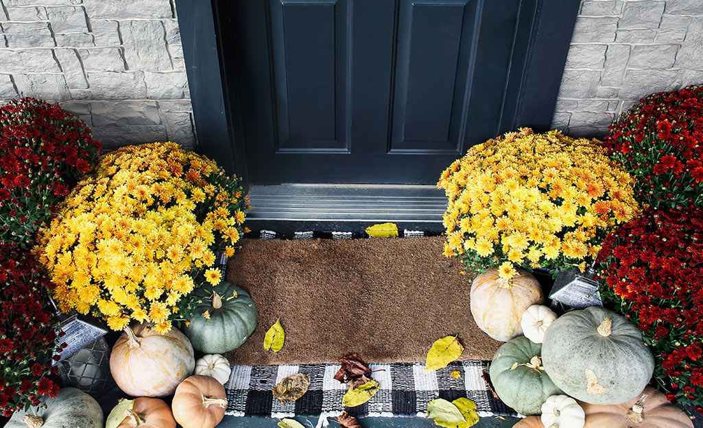 A fall porch decorated with fall planters and pumpkins.