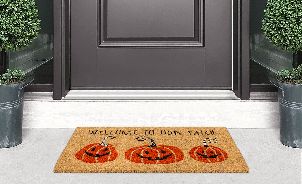 Fall porch decor includes decorative doormats.