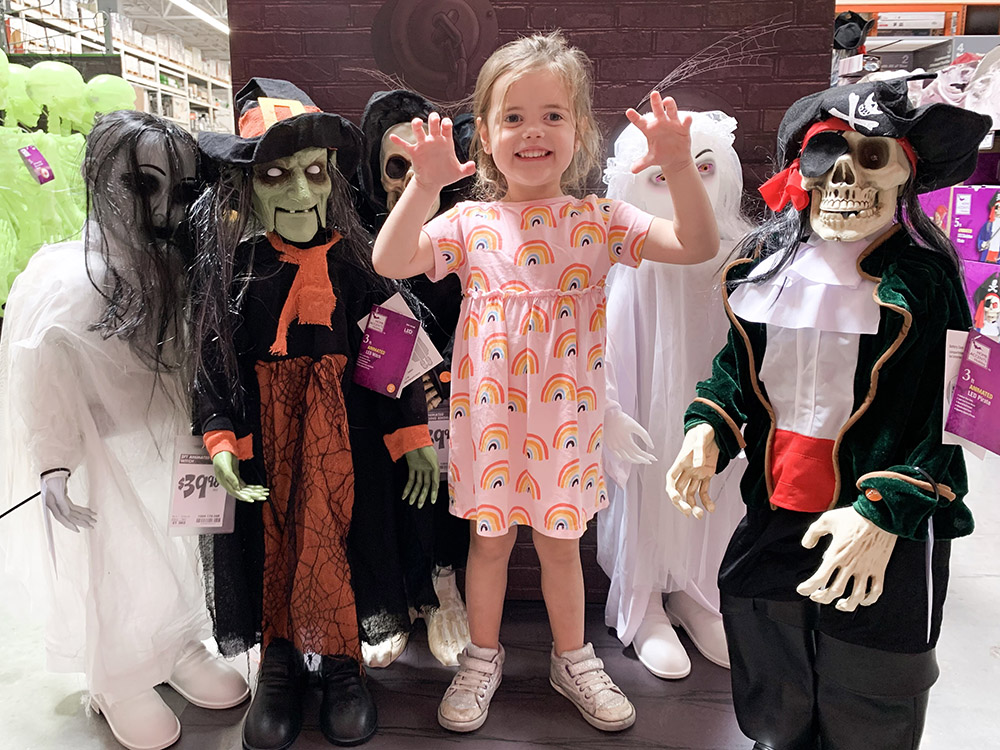 A young girl standing with a group of Halloween dolls.