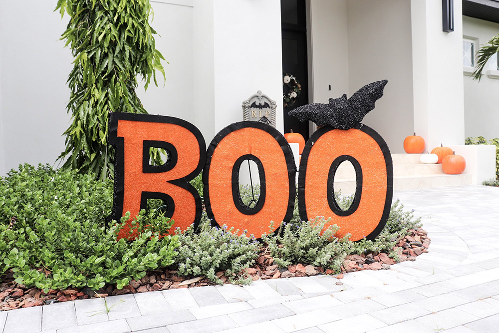 A bat sitting on top of a large orange and black Boo sign.