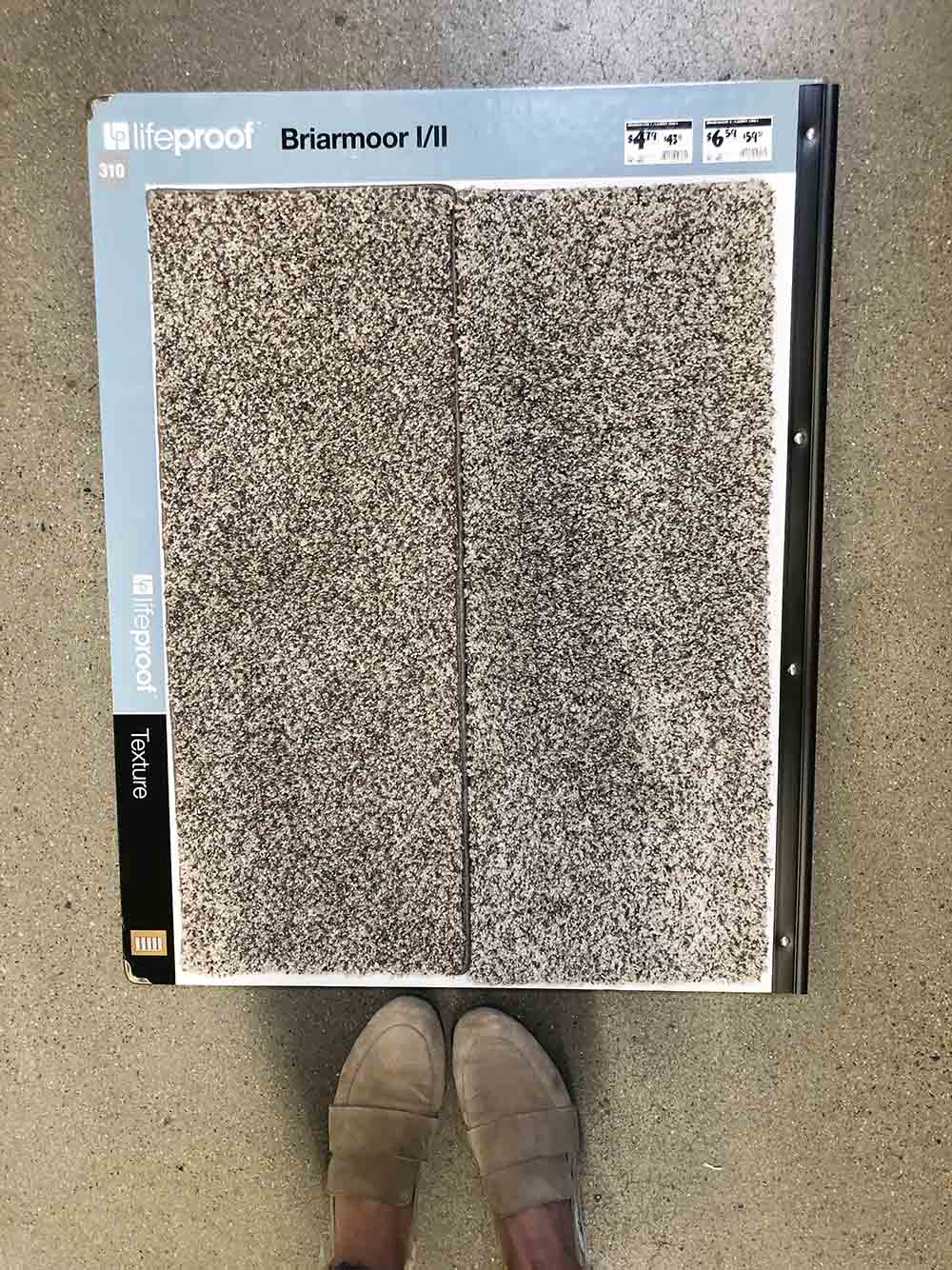 A person standing over two samples of Lifeproof carpet.