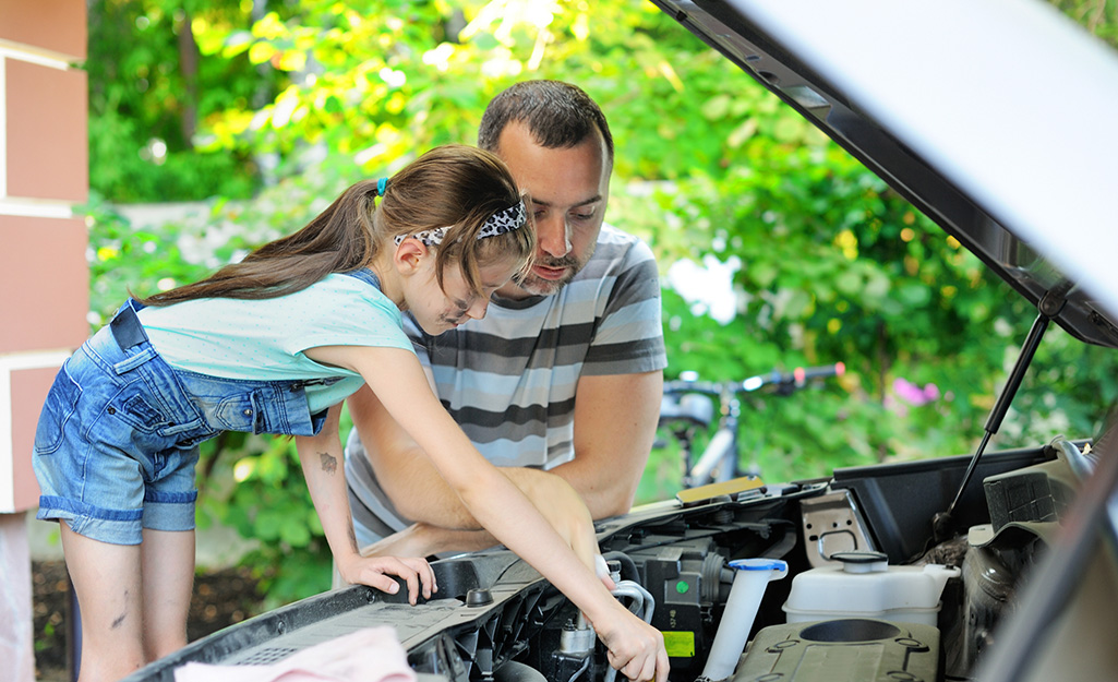 Father and daughter working on car engine.