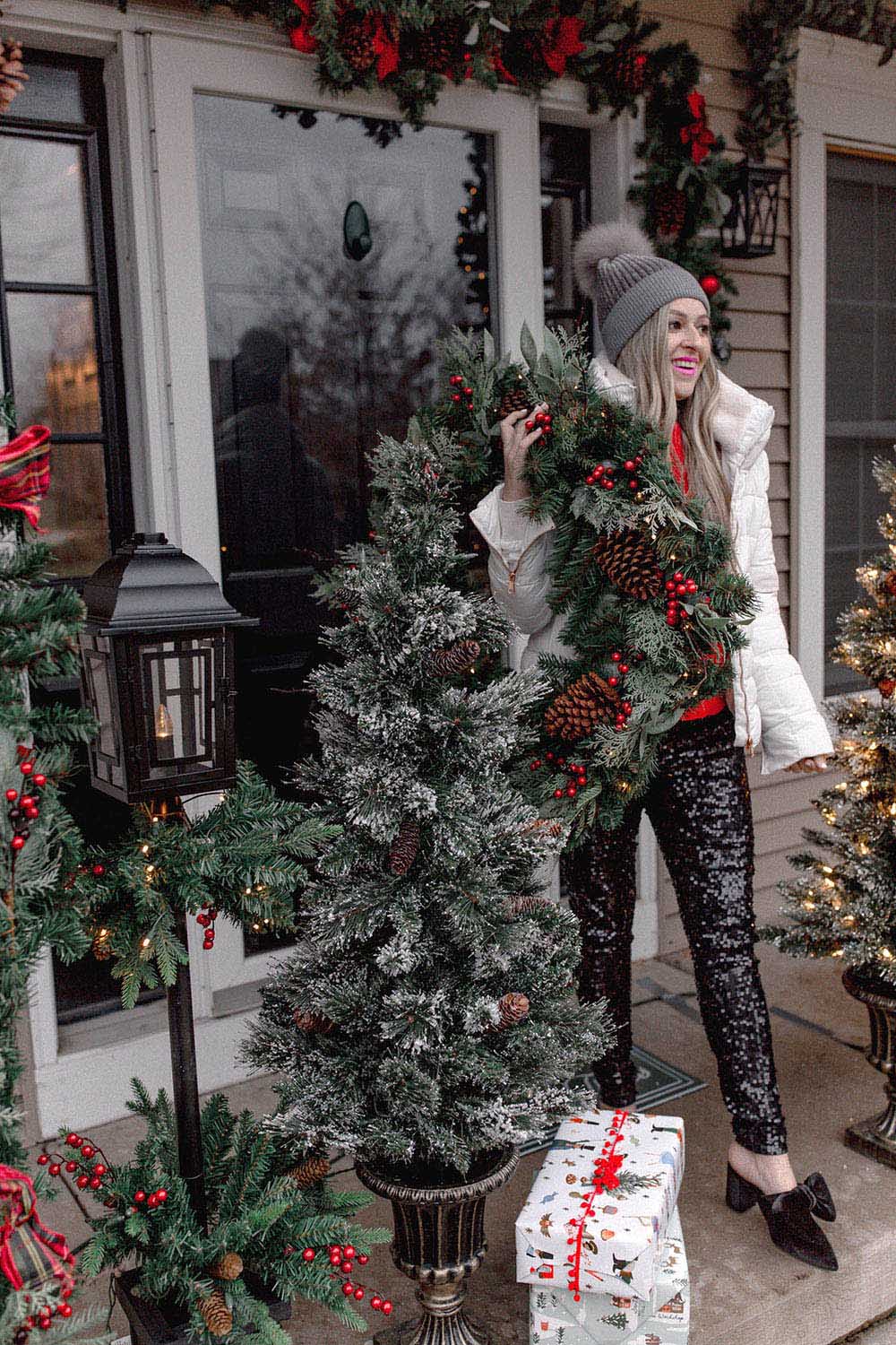 A person standing next to a Christmas tree on front porch