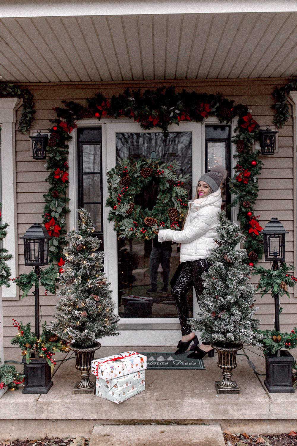 A person standing on front porch with Christmas decorations