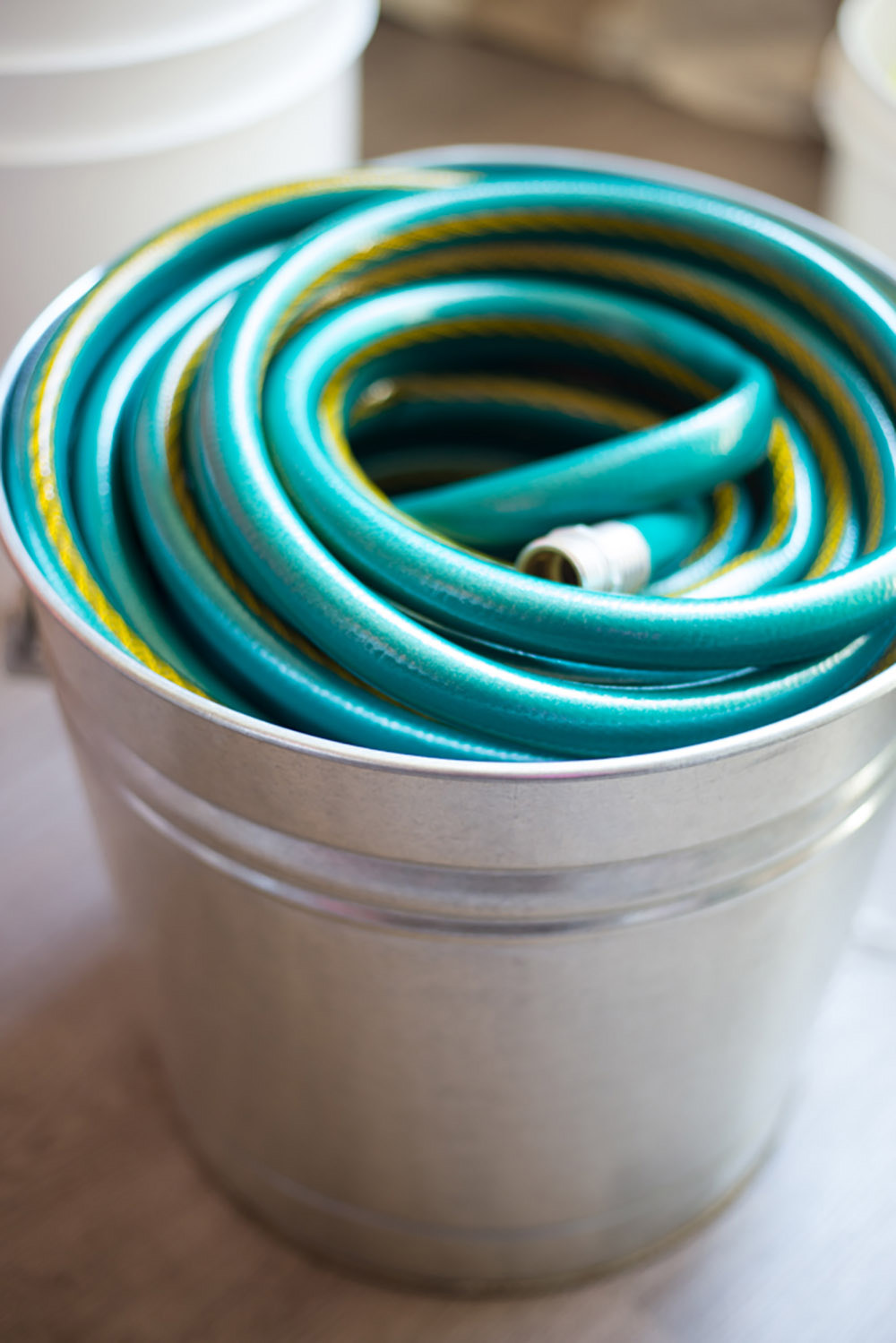 A garden hose wrapped inside a galvanized bucket.