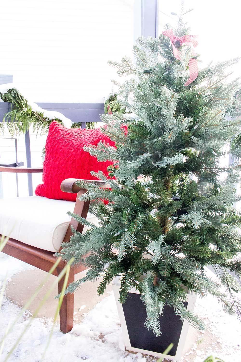 A small Christmas tree on a front porch 