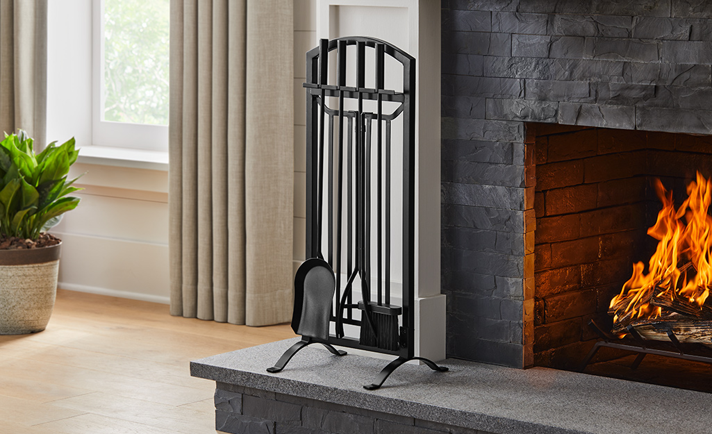 Black stone fireplace accessories beside a wood-burning fireplace.