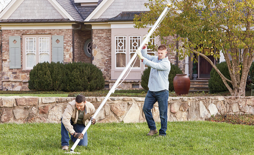 Two people raising a flag on a newly installed flag pole