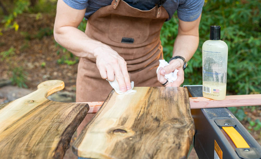 A person applies food-safe finish to a wooden board.