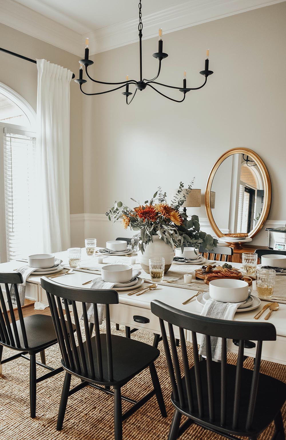 A dining table decorated with place settings and fall colored flowers for Friendsgiving.