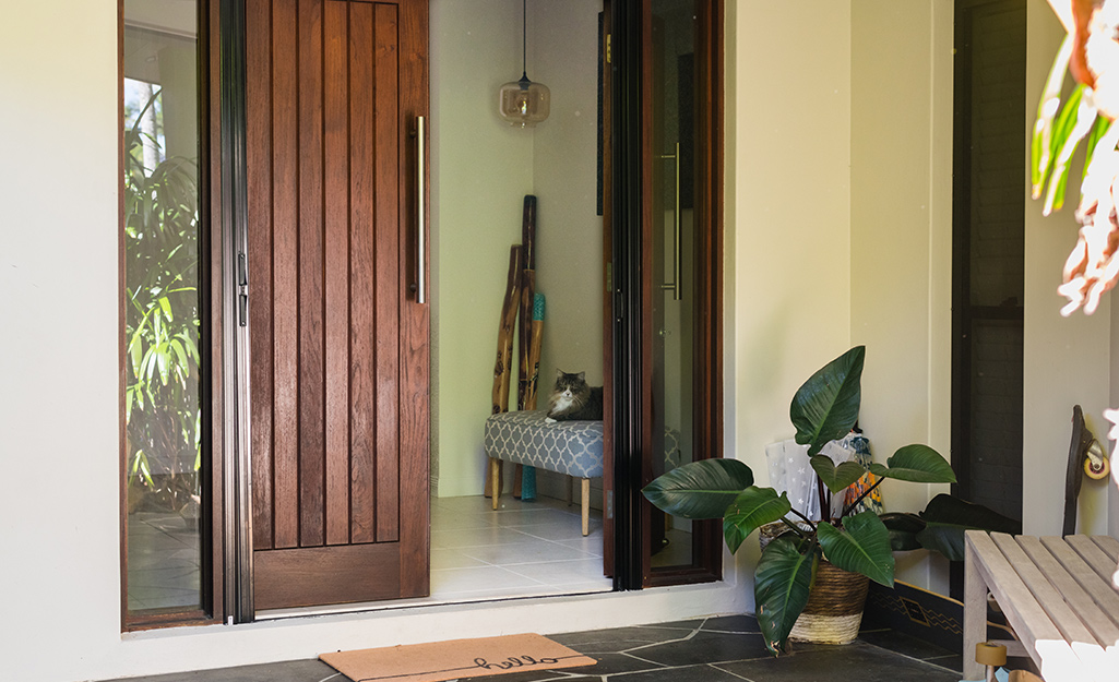 A modern front door with wooden slats and a large metal handle. 