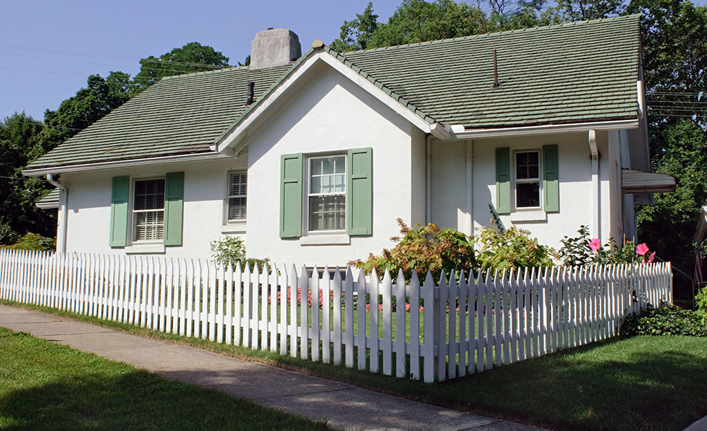 A white picket fence surrounds the front yard of a cottage.