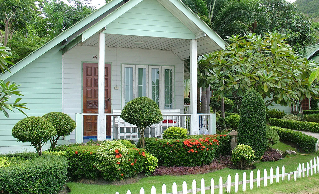 A small home with manicured bushes and flowers.