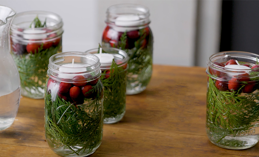 DIY candle holders made with mason jars filled with water, cranberries and floating candles