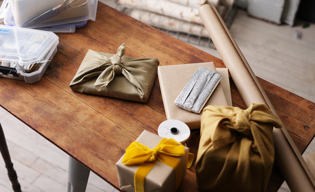 Gifts wrapped in linen,  a roll of craft paper and other holiday supplies