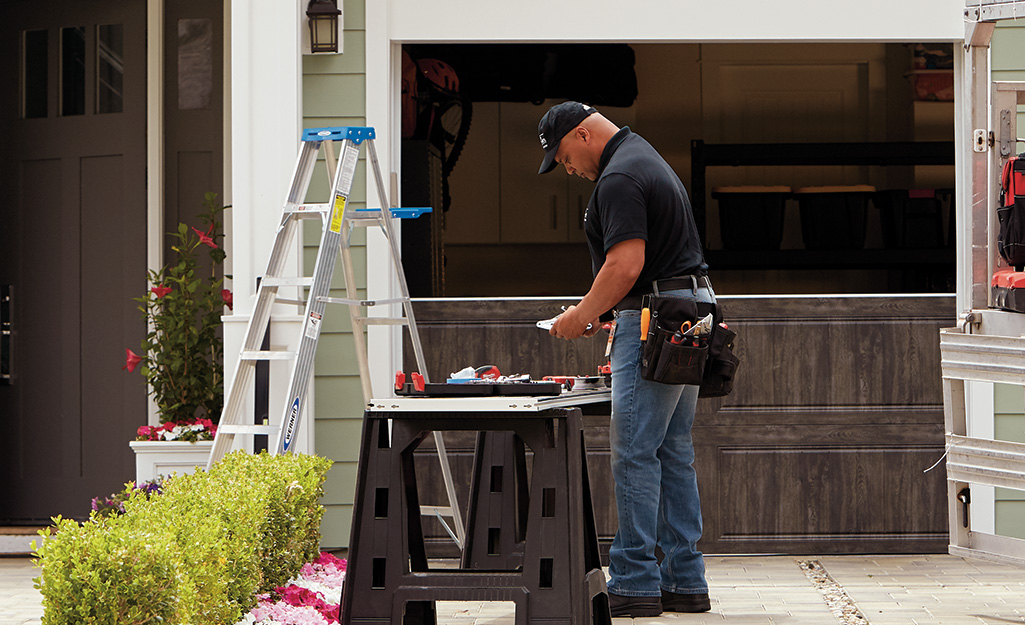 A man gathers tools for garage door maintenance. A man gathers tools for garage door maintenance.