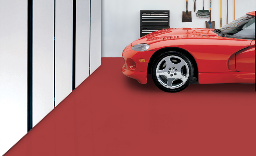 A red car parks on a garage floor painted red.