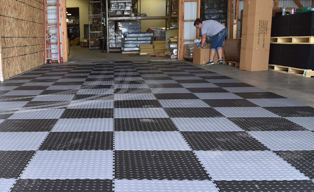Interlocking tiles cover a garage floor in a black and gray checkerboard pattern.