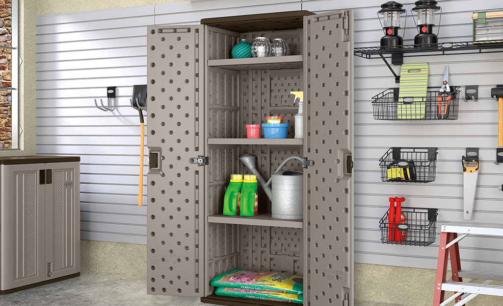 A storage cabinets against a garage wall holds gardening supplies.
