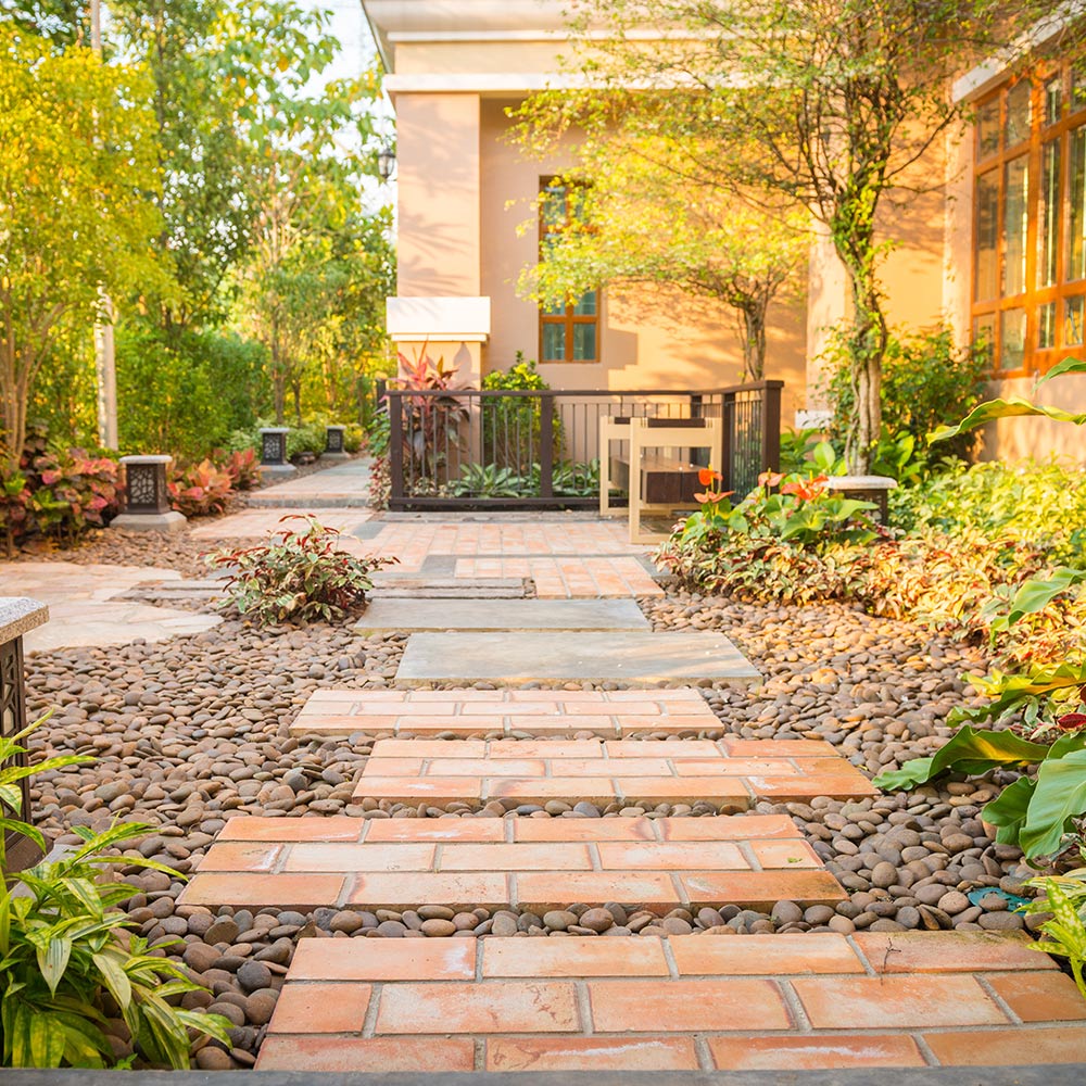 A paver path in a gravel walkway through a garden.