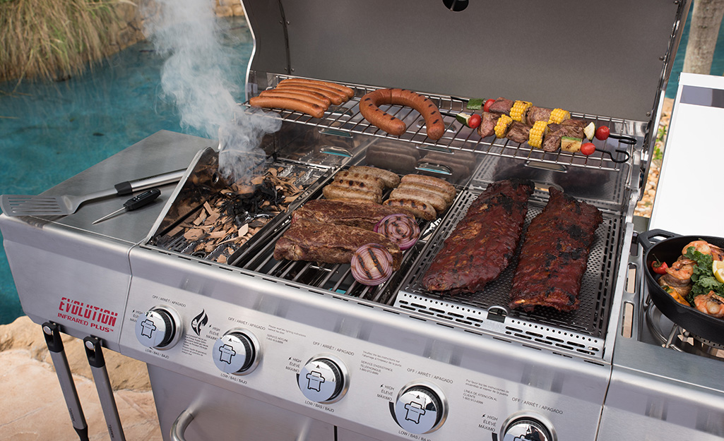 Ribs, sausage, skewers and other foods cook on an infrared gas grill.