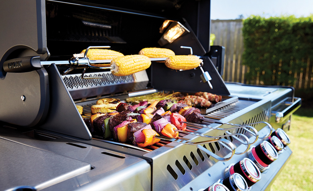 Corn on the cob turns on a rotisserie rotation accessory on a gas grill.