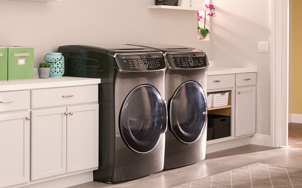 A black front-load washer and gas dryer sit side-by-side in a laundry room.