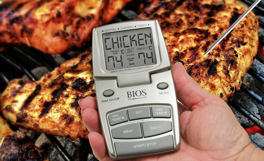 A person uses a wireless meat thermometer to grill. 