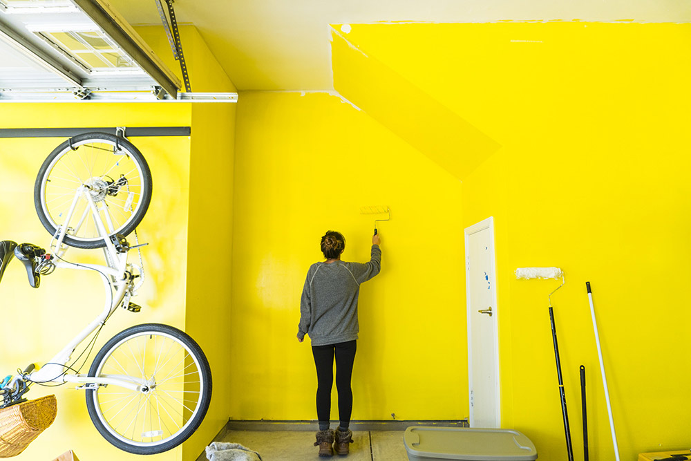 A person painting the garage wall yellow