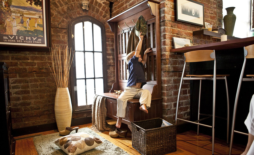 A child sitting on a hall tree as he hangs up his hat. A child sitting on a hall tree as he hangs up his hat.
