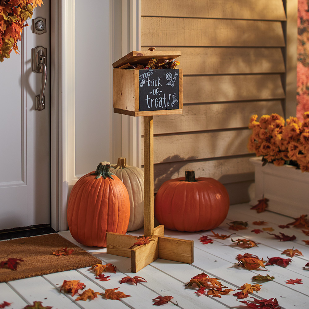 A finished halloween candy holder sits on a porch with pumpkins. A finished halloween candy holder sits on a porch with pumpkins.